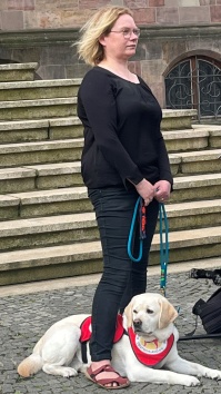 Kampagne Assistenzhund Willkommen Frau mit Asistenzhund mit rotem Leibchen
