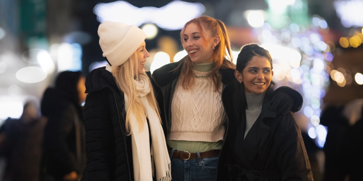 Drei Freundinnen schlendern mit Einkaufstüten durch die winterliche Innenstadt