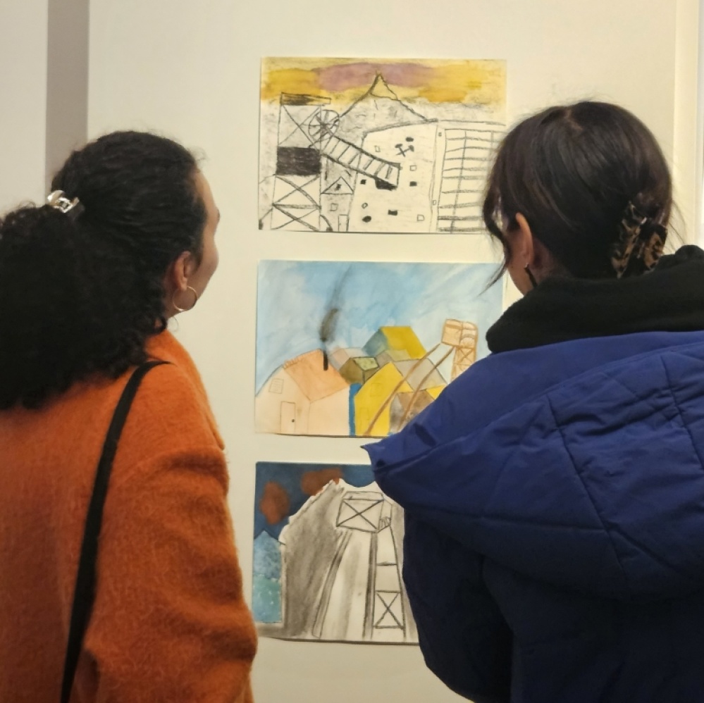 Besucherinnen vor Stellwand mit drei Kinderzeichnungen