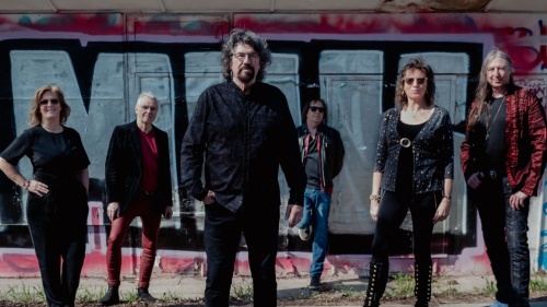 Phil Bates Band Die sechs Mitglieder der Phil Bates Band stehen vor einer mit Graffiti bemalten Wand