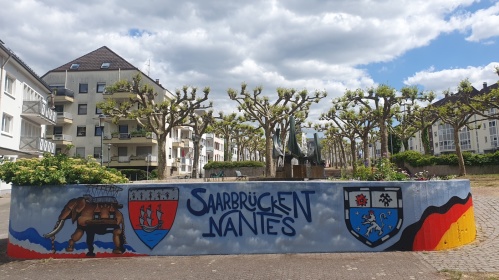 Mauer "Saarbrücken-Nantes" am Nanteser Platz Eine Mauer bemalt mit dem Elefanten aus Nantes, den Stadtwappen Nantes-Saarbrücken und dem Schriftzug "Saarbrücken-Nantes"