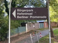 Schild mit dem Schriftzug "Bürgerpark Hafeninsel Berliner Promenade"