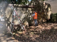 Ein Mann in Warnkleidung reinigt eine alte Mauer mit einem Hochdruckreiniger