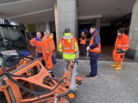 Menschen in Warnwesten stehen mit einem Reinigungsfahrzeug in einer Einkaufsstraße