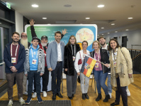 Eine Gruppe Menschen posiert vor einer Tafel für ein Gruppenbild 