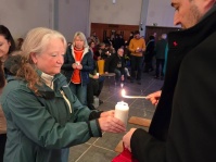 Ein Mann entzündet die Kerze einer Frau in einer Kirche