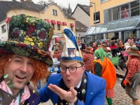 Eine Gruppe mit neon-grünen Perücken und auffälligen Kostümen posiert lächelnd vor den Zuschauern.