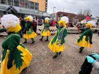 Eine Gruppe kostümierter Personen mit transparenten Gewändern und bunten Regenschirmen zieht an den Zuschauern vorbei.