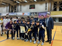 Eine Jungend-Fußballmannschaft mit Medallien um den Hals stehen in einer Halle, links und rechts  stehen noch Erwachsene
