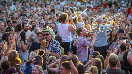 Saxophonist und Posaunisten musizieren direkt in der jubelnden, tanzenden Menschenmenge.