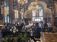 Ein Pianist spielt vor Publikum in einem festlich beleuchteten Saal mit großen Kronleuchtern und bunten Glasfenstern.